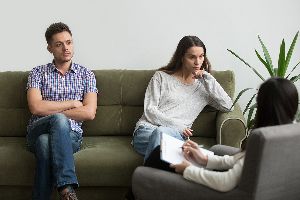 Couple Sitting On Couch Talking To A Therapist.